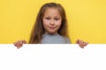 Place for your advertisement. Baby girl pointing to blank white billboard on yellow background, copy space. Emotions Royalty Free Stock Photo