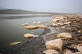 Placers of large stones on the banks of a drying lake among the hills. Royalty Free Stock Photo