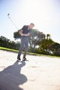 Placing all of his focus on the ball. a handsome mature man playing a game of golf. Royalty Free Stock Photo