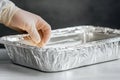 Placing food into an aluminum container in a kitchen setting during food preparation is being done hand in glove Royalty Free Stock Photo