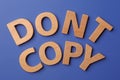 Plagiarism concept. Phrase Don`t Copy made of wooden letters on blue background, top view