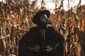 Plague doctor gothic woman standing in autumn thickets of corn. Creepy raven mask, halloween, historical terrible Royalty Free Stock Photo