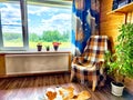 A plaid chair sits by a window with a view of a green forest and a blue sky Royalty Free Stock Photo