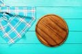 Plaid tablecloth and brown cutting board for pizza on blue wooden table. Top view and copy space. Mock up Royalty Free Stock Photo