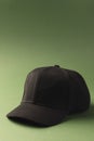 A plain black baseball cap is positioned against a green background, with copy space Royalty Free Stock Photo