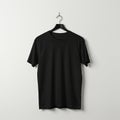 A plain black T-shirt hangs on a black plastic hanger against a white background. The Royalty Free Stock Photo