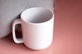 Plain blank white 11oz cup in front of a grey cushion on a pink shiny surface Royalty Free Stock Photo