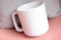 Plain blank white 11oz cup in front of a grey cushion on a pink shiny surface Royalty Free Stock Photo