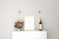 Plain canvas with frame for Mock up on dresser shelf, flower and vase, bottle wine and glass. White wall Background. Royalty Free Stock Photo