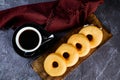 Plain Donuts with cup of black coffee served on wooden board isolated on napkin top view of baked food breakfast on table