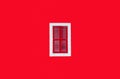 Plain red wall with a red window in a white frame in the middle of the shot Royalty Free Stock Photo