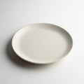 Plain round ceramic plate with a smooth, matte finish on a white background. Simple and minimalistic Royalty Free Stock Photo