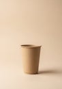 A plain, tan-colored paper cup is set against a matching tan background, emphasizing Royalty Free Stock Photo