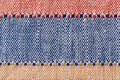 Plain weave fabric macro background. Textile with horizontal strips of red, blue, yellow colors. Detail of cloth texture surface. Royalty Free Stock Photo