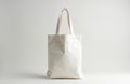 Plain white canvas tote bag presented front view on a light grey background. It has two handles and a simple rectangular shape, Royalty Free Stock Photo