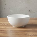 A plain white ceramic bowl on a wooden surface. The smooth, round bowl contrasts Royalty Free Stock Photo
