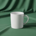 A plain white ceramic mug with a curved handle is placed on a green cloth Royalty Free Stock Photo