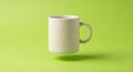 A plain white ceramic mug floats above a solid green background. The mug\'s cylindrical shape and Royalty Free Stock Photo