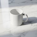 A plain white ceramic mug with a handle sits on a polished white marble surface. Light Royalty Free Stock Photo