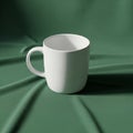 A plain white ceramic mug is placed on a green, fabric-covered surface Royalty Free Stock Photo