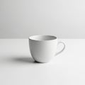 A plain white ceramic mug is placed on a light surface against a neutral background. Royalty Free Stock Photo