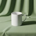 A plain white ceramic mug is placed on a textured green fabric backdrop Royalty Free Stock Photo