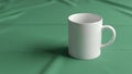 A plain white ceramic mug stands on a smooth green fabric background Royalty Free Stock Photo