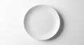 A plain, white ceramic plate sits on a smooth, light gray surface. The plate is circular Royalty Free Stock Photo