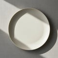 A plain white ceramic plate on a textured light gray surface Royalty Free Stock Photo