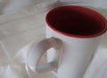 A plain white cup on a textured white cloth