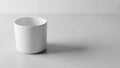 A plain white cylindrical cup sits on a smooth light gray surface Royalty Free Stock Photo