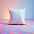 A plain white pillow rests on a colorful patterned surface with a gradient background lighting the shot Royalty Free Stock Photo