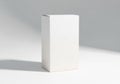 A plain white rectangular box stands on a flat surface, casting a Royalty Free Stock Photo