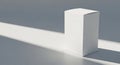 A plain white rectangular cardboard box stands on a smooth, flat gray surface. It Royalty Free Stock Photo