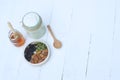 Plain yoghurt in white bowl, honey, cereal, raisin and wood spoon on white wooden table background Royalty Free Stock Photo