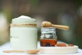 Plain yoghurt in white bowl, honey, cereal, raisin and wood spoon on white wooden table background