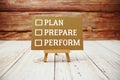 Plan, prepare, perform text message with easel on wooden background Royalty Free Stock Photo