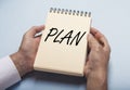 Plan word on notebook in male hands over blue table Royalty Free Stock Photo