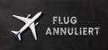 Plane on a black background with german text flug annuliert, in english flight cancelled Royalty Free Stock Photo