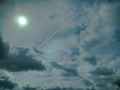 Plane contrails on a dramatic cloudy sky with bright sun out in the sky.