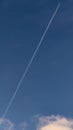 A plane crosses the blue sky diagonally leaving behind a long white trail Royalty Free Stock Photo