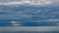 The plane flies on the background of clouds over the sea, through the clouds make their way the sun, the French Riviera Royalty Free Stock Photo