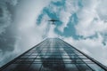 The plane flies over a modern glass skyscraper Royalty Free Stock Photo