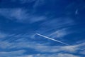 a plane flying against a blue sky with Cirrus Cumulus clouds Royalty Free Stock Photo