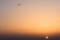 Plane flying high in the sky above the setting sun Royalty Free Stock Photo