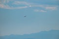 Plane flying in light blue sky and mountains in the distance