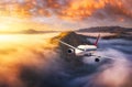 Plane is flying over mountains in low clouds at golden sunrise Royalty Free Stock Photo