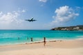 Plane land over people on beach of philipsburg, sint maarten. Jet flight low fly over blue sea. Airplane in cloudy blue sky. Beach