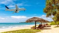Plane landing at Caribbean resort, airplane flies over tropical ocean beach Royalty Free Stock Photo