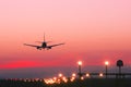 Plane landing at runway on the background of red sunset Royalty Free Stock Photo